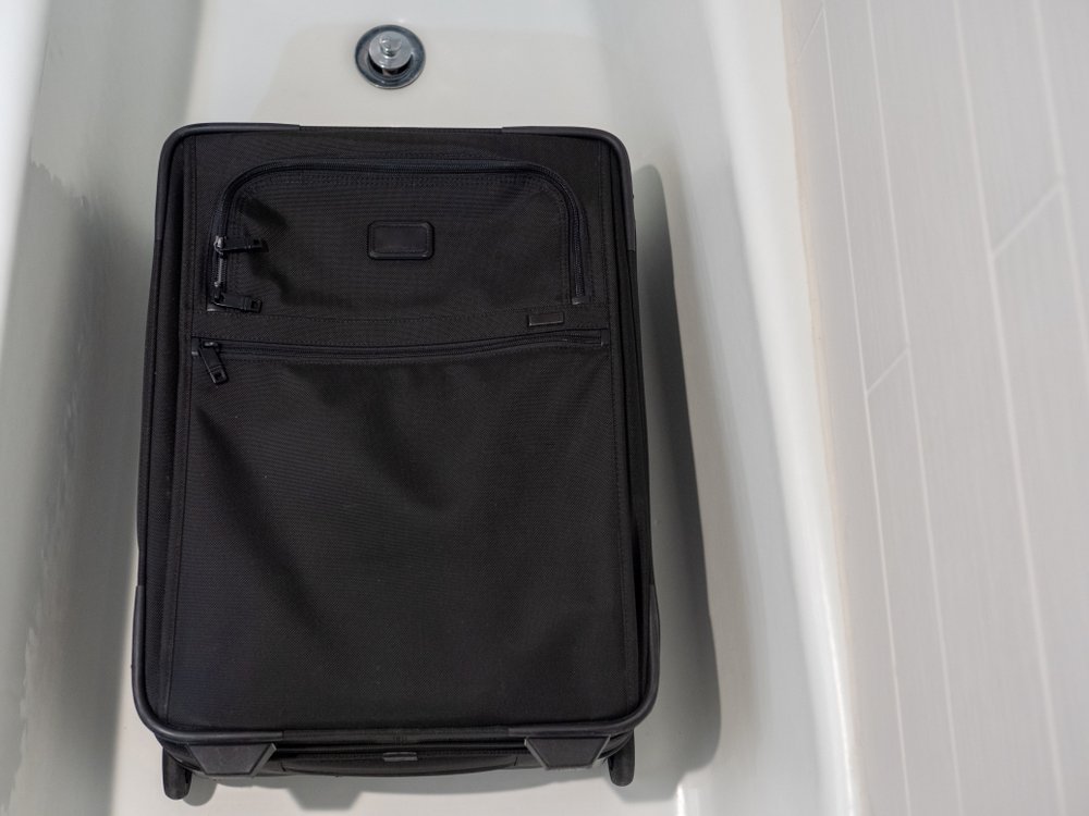 black suitcase in a white bathtub